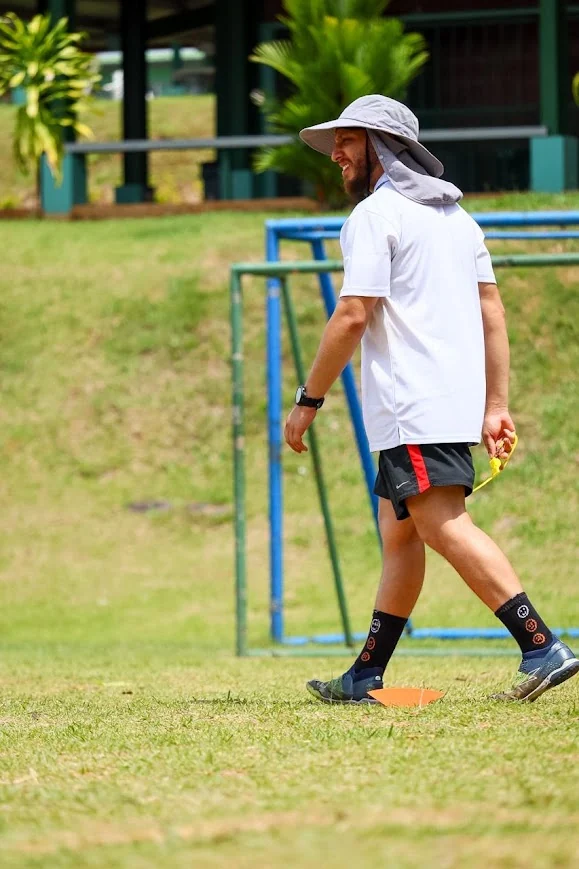 Diego Gentile Ventura Martinez caminando y observando una sesión de entrenamiento en una cancha de fútbol